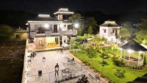 Un edificio de dos pisos con un patio, asientos al aire libre y un pequeño jardín.