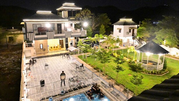 Un hotel moderno con piscina, zona de estar al aire libre y un jardín bien iluminado.