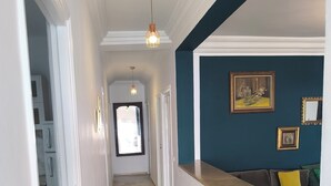 Een gang met een marmeren vloer, witte muren, een blauwe accentmuur en een zithoek met kussens.