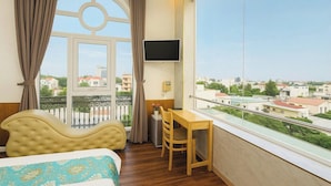 Habitación de hotel con cama, escritorio y ventana grande con vista a la ciudad.