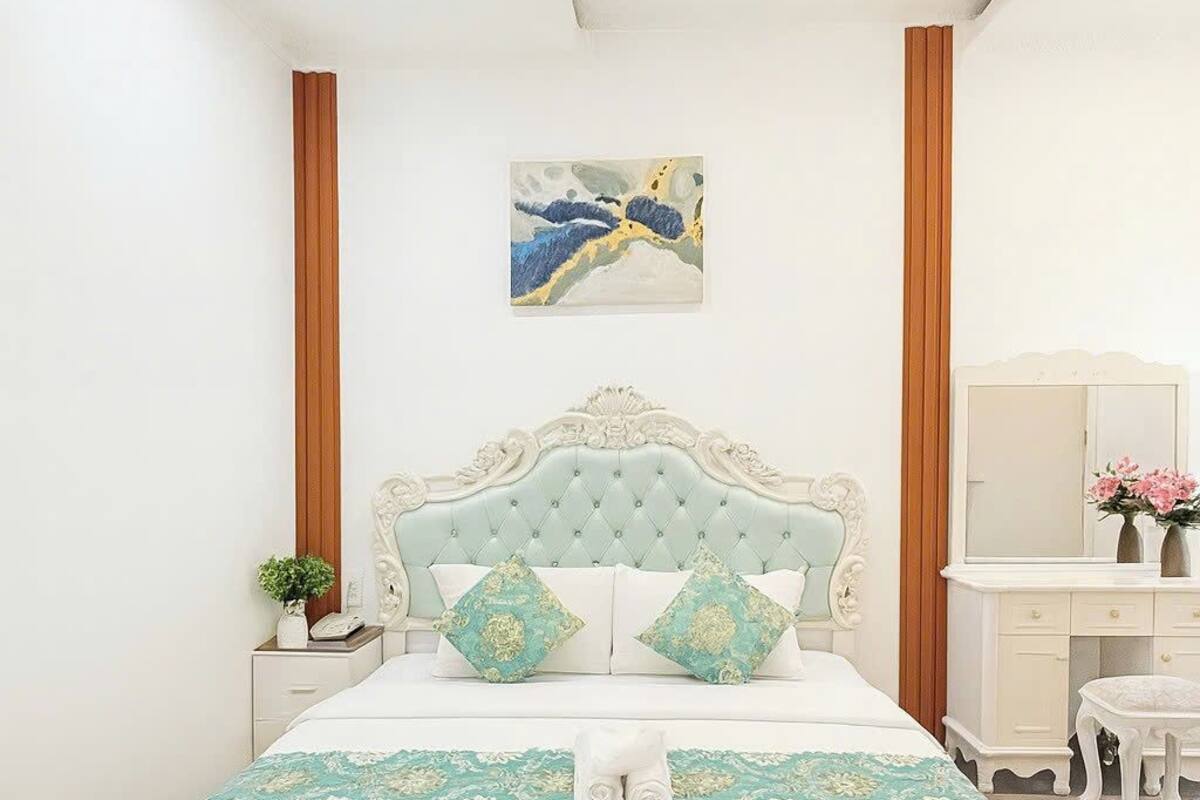 Une chambre à coucher avec un grand lit, une table de chevet, une commode et un miroir.