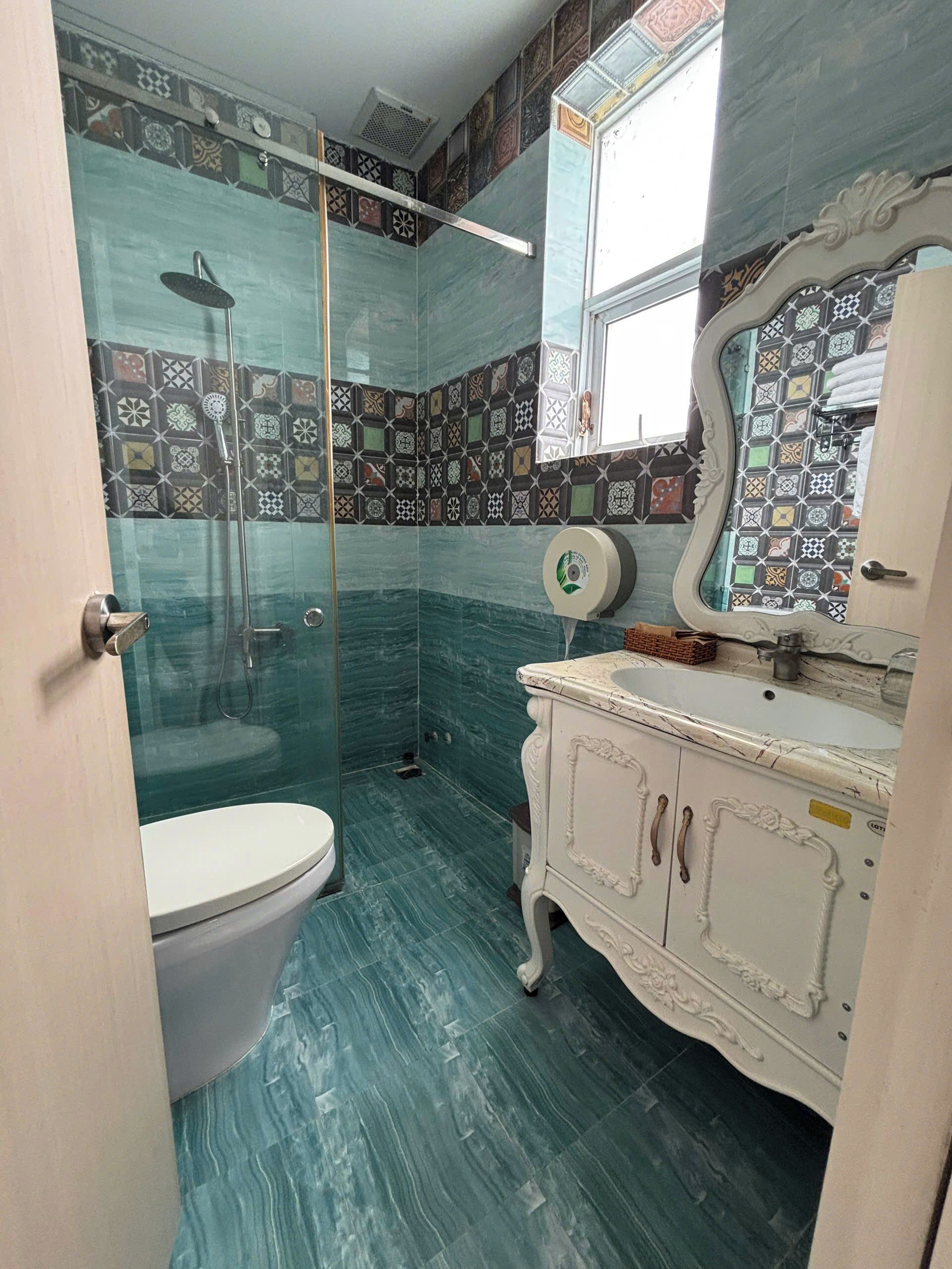 Een badkamer met toilet, douche en wastafel met spiegel.