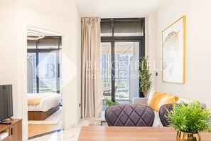 Une chambre d’hôtel moderne équipée d’un lit, d’un canapé, d’une télévision et d’une grande fenêtre donnant sur la ville.
