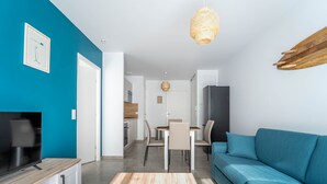 Una sala de estar moderna con un sofá color turquesa, una mesa de centro de madera y un televisor sobre un mueble de madera.