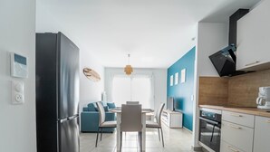 Una cocina moderna con un refrigerador negro, un área de comedor con un sofá azul y una encimera de madera con una cafetera.