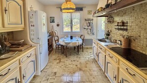 Une cuisine équipée d’une table à manger, de placards, d’un réfrigérateur et d’un luminaire suspendu.