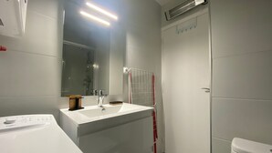 A modern bathroom with a white sink, mirror, and toilet. - Cozy apartment near the Thermal Baths in Balaruc-les-Bains (Balaruc-les-Bains)
