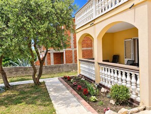 Un patio con un camino empedrado, un árbol y un edificio con balcón.