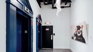 A hallway with black doors, a white wall with a framed artwork, and a sign indicating an exit. - Chic 2BR/2BA Stay | Downtown & Capitol Views (Montgomery)