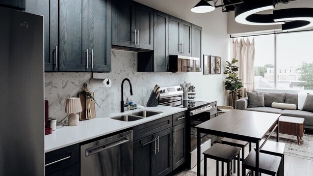 A modern kitchen with dark cabinets, a dishwasher, and a dining area with a table and chairs. - Chic 2BR/2BA Stay | Downtown & Capitol Views (Montgomery)