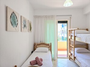 Une chambre avec un lit simple, un lit superposé et une fenêtre avec des rideaux.