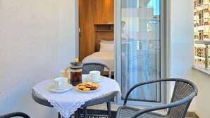 A balcony with a table set for breakfast, a private room with a bed, and a view of a building under construction. - Modern Apartment a Short Walk from the Beach (Durres)