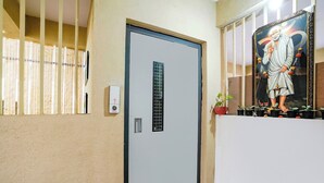 Una porta con un oblò verticale, un citofono a parete e un quadro incorniciato sopra.