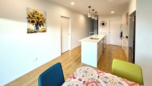A modern kitchen with a central island, a dining area with two chairs, and a wall-mounted clock. - Newly Built 3 BDMs Besides Chartwell Shopping Mall (Hamilton)