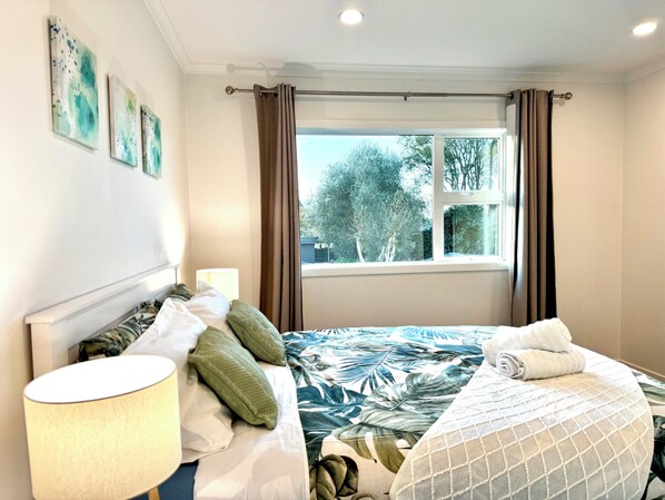 Une chambre d’hôtel avec un lit, une lampe et une fenêtre avec des rideaux.