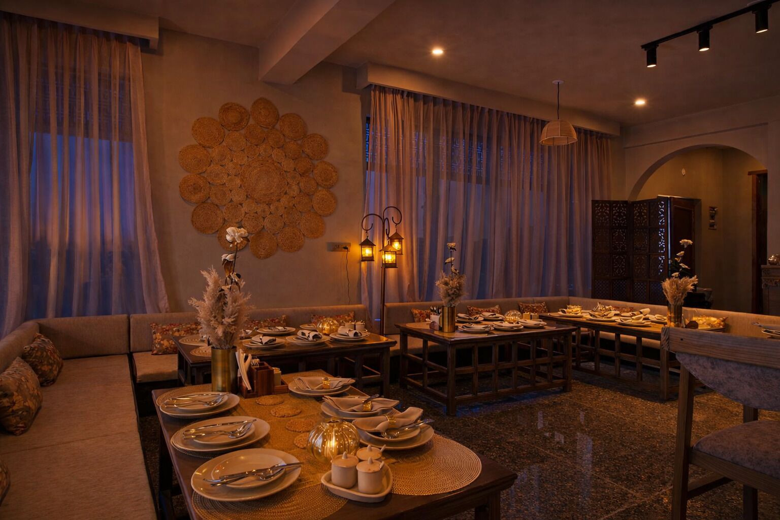 A dining area with round tables set for a meal, a sofa, and a decorative wall.