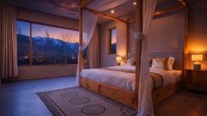 A four-poster bed with a view of mountains through the window. - The Vintage Villas Resort Ladakh - Luxury Stay with Mountain Views (Leh)