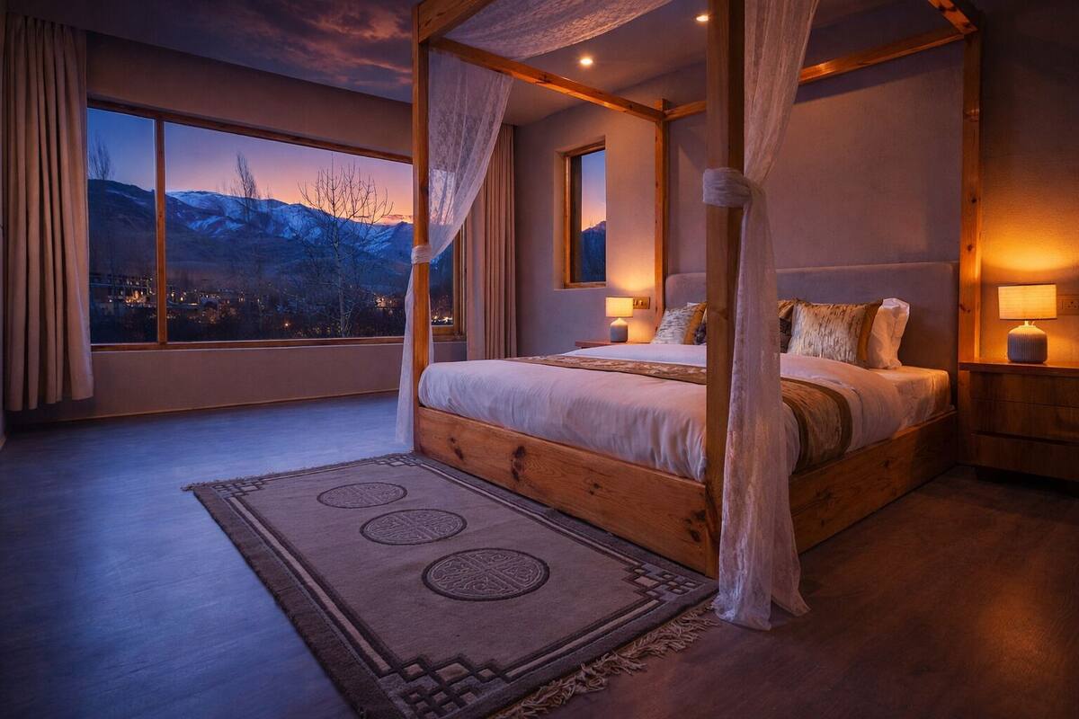A four-poster bed with a view of mountains through the window.