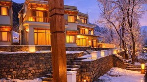A multi-story building with a stone facade, wooden balconies, and a stone staircase leading to the entrance. - The Vintage Villas Resort Ladakh - Luxury Stay with Mountain Views (Leh)