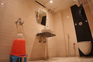 Un baño con inodoro, lavabo, espejo, ducha y una silla roja.