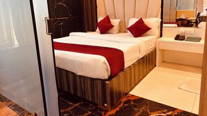 A modern hotel room with a large bed, a bedside table with a phone and a book, and a mirror above the bed.