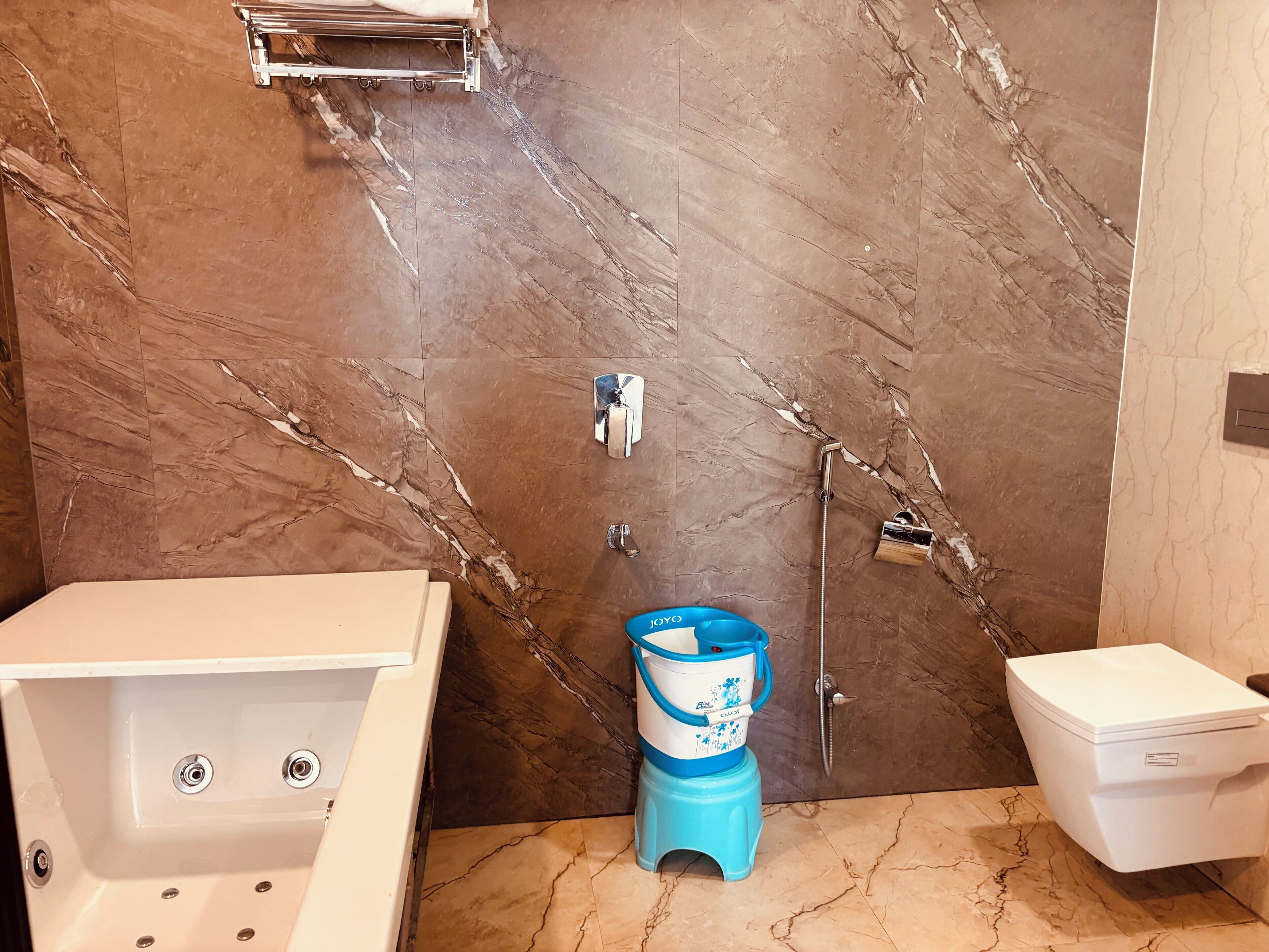 Kylpyhuone, jossa on marmoriseinä, kylpyamme, wc ja sininen juomavesiautomaatti.
