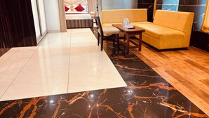 A hotel lobby with a modern design, featuring a marble floor, a sofa, a small table, and a chair.