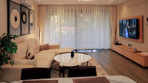 A modern living room with a sofa, round coffee table, and a TV mounted on the wall. - Abrish Hotel and Apartment (Kampala)