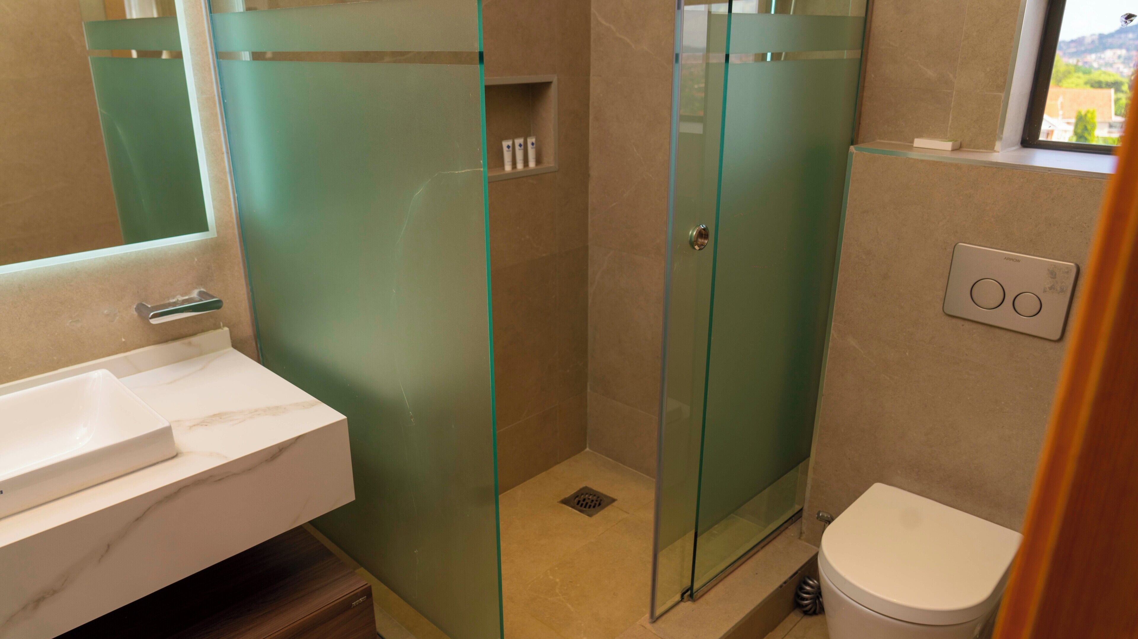 Un bagno moderno con doccia vetrata, lavandino bianco e water.