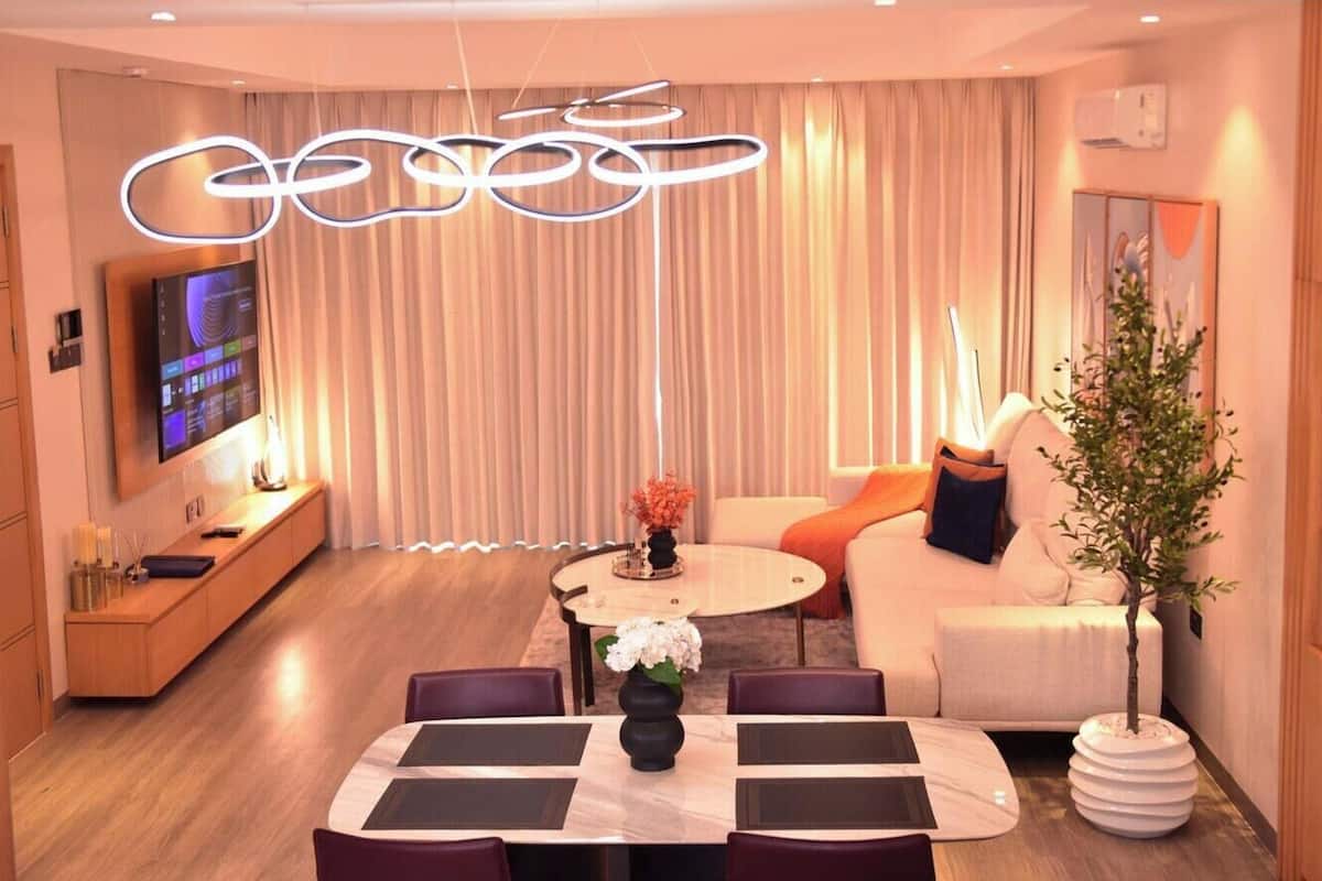 A modern living room with a dining area, a flat-screen TV, and a decorative plant.