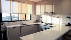 A modern kitchen with a large window, marble countertops, and built-in cabinets. - Abrish Hotel and Apartment (Kampala)