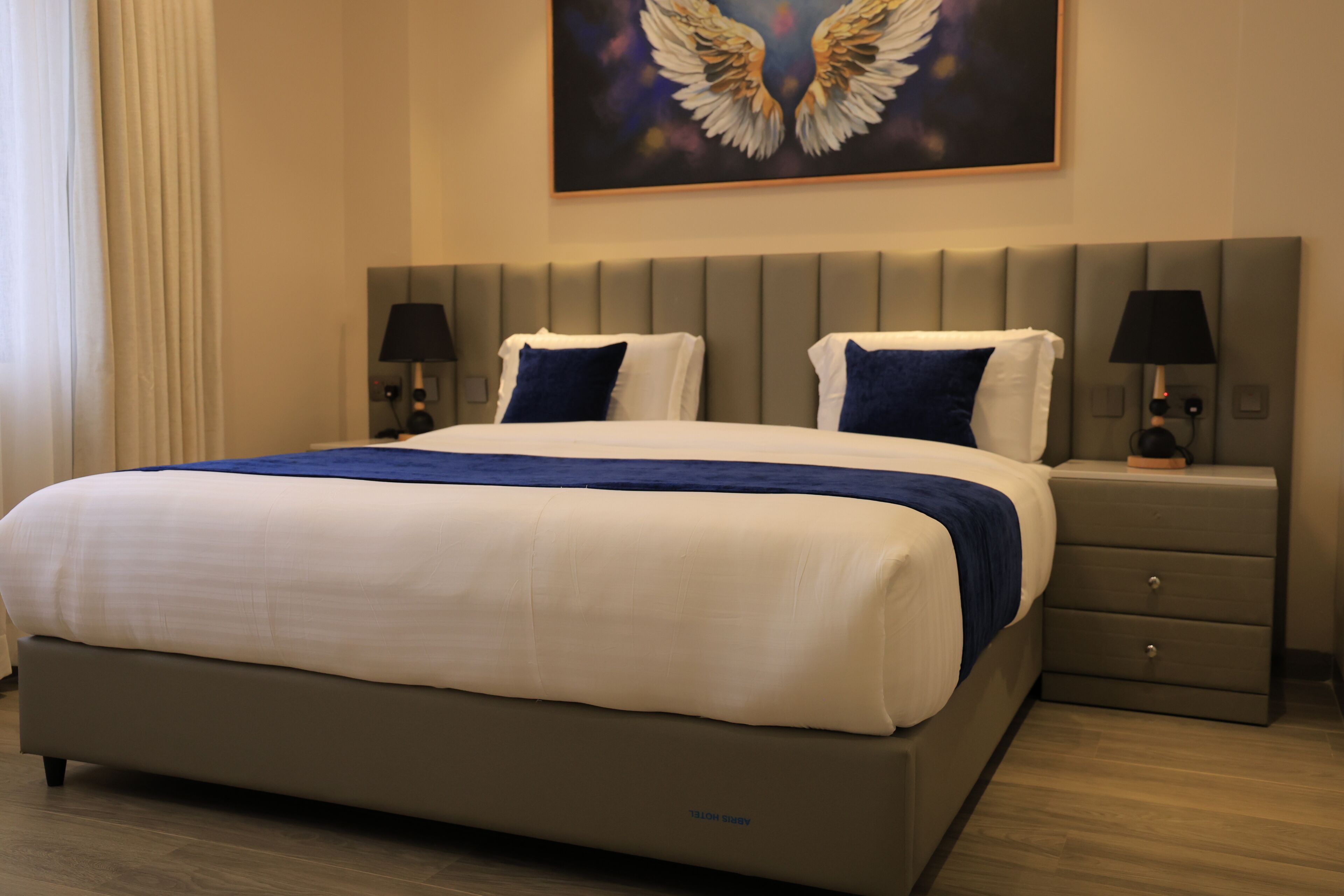 A hotel room with a large bed, two bedside tables, and a wall-mounted lamp.