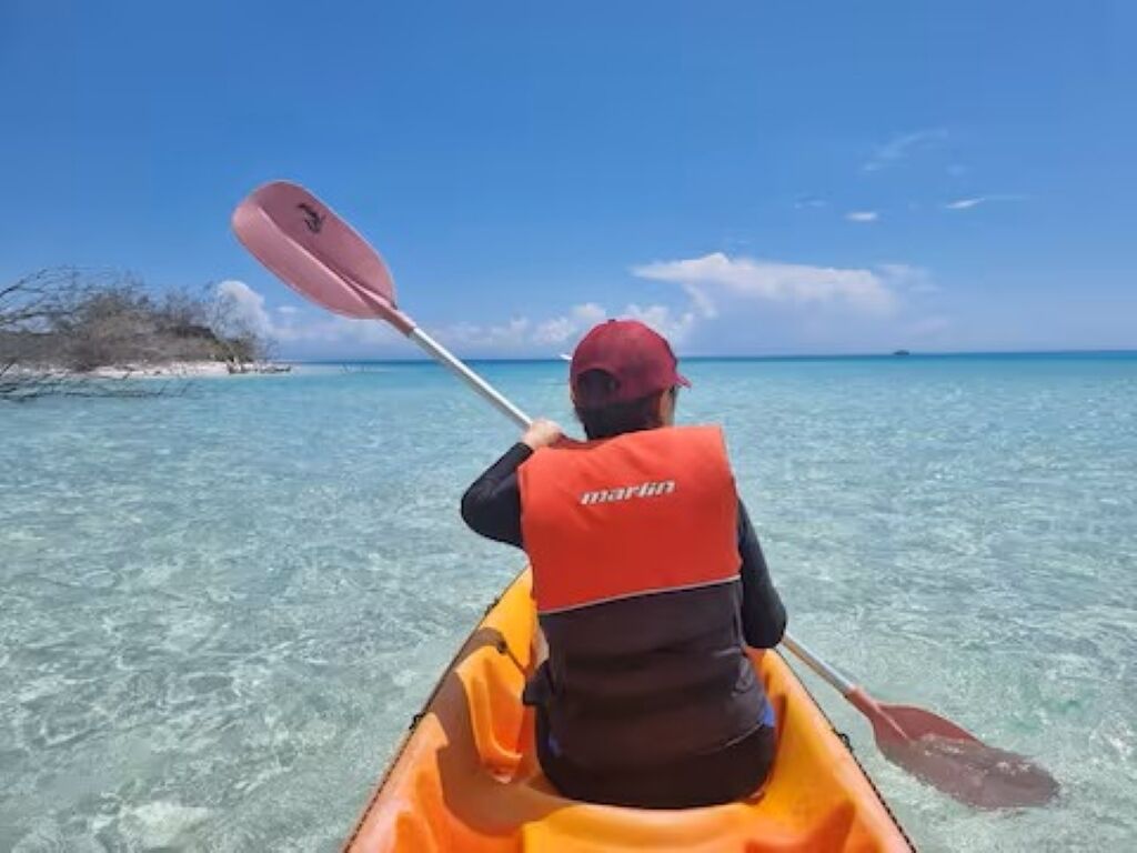 Une personne dans un kayak, sur une eau claire.