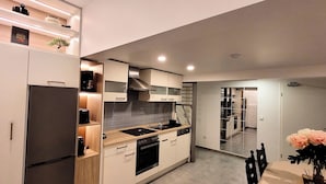 A modern kitchen with built-in appliances, a dining area with a table and chairs, and a small potted plant. - MoselVilla No7 Deluxe Apartment (Pommern)