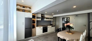 A modern kitchen with built-in appliances, a dining area with a table and chairs, and a staircase leading to another level. - MoselVilla No7 Deluxe Apartment (Pommern)