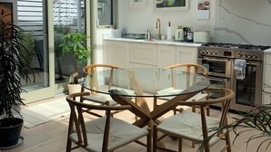 A modern kitchen with a glass dining table, wooden chairs, and a built-in oven.