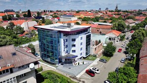 A modern hotel with a glass facade, a rooftop terrace, and a parking area. - Hotel Excelsior (Timisoara)