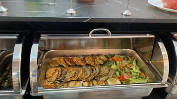 Un bufé con diversos alimentos, incluyendo opciones fritas y una ensalada de verduras.