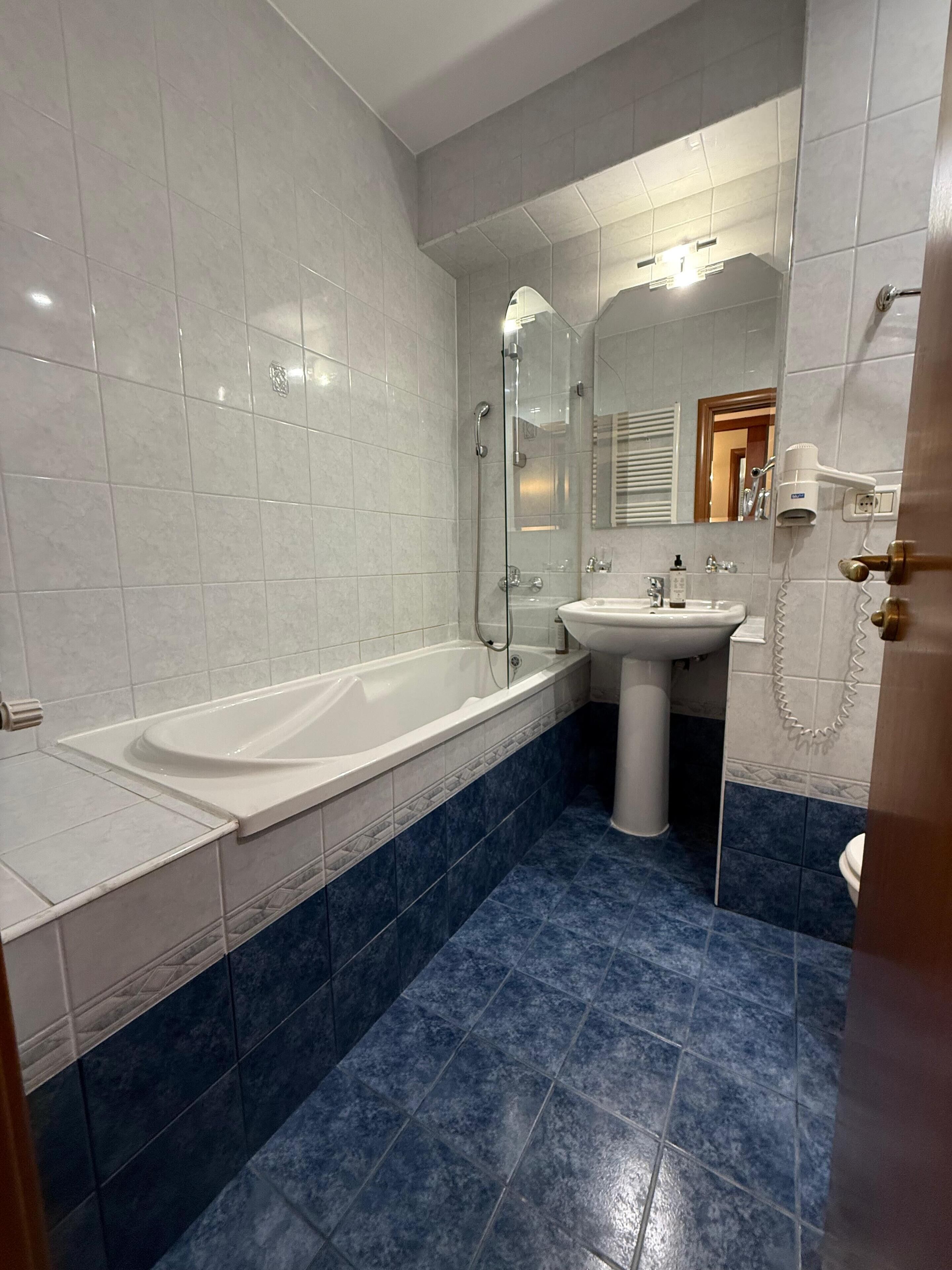 Een badkamer met een bad, wastafel en spiegel.