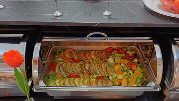 Un bufé con papas en rodajas, verduras mixtas y una tulipán roja.