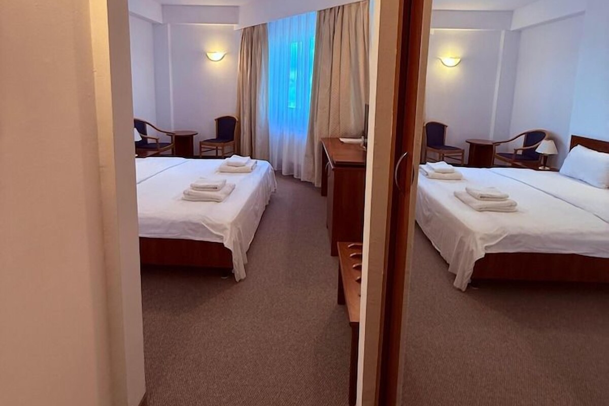 A hotel room with two beds, a desk, and a chair.
