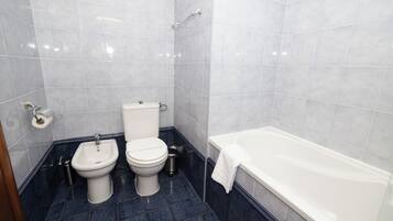 A bathroom with a toilet, bidet, and bathtub.