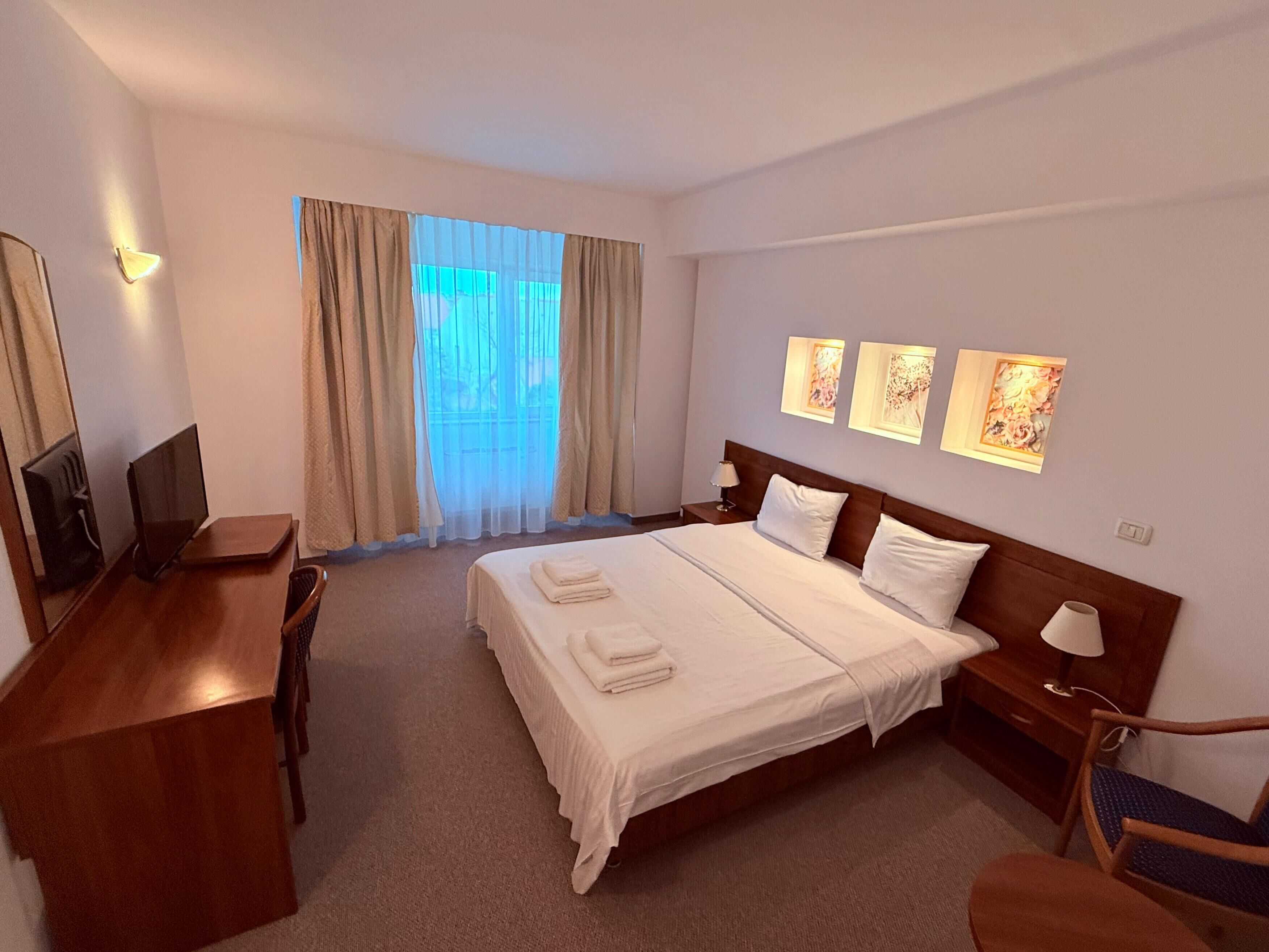 Una habitación de hotel con una cama grande, un escritorio, una silla y un televisor.