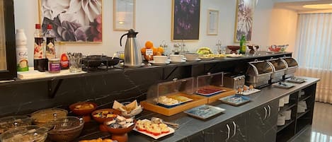 A buffet with various food items and condiments, including fruits, pastries, and beverages.