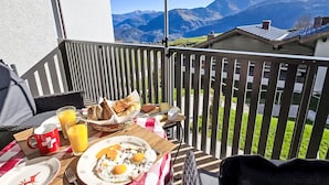 A balcony with breakfast items, including eggs and bread, and a Swiss flag mug. - Nice apartment for 4 people with WIFI, pool, TV, balcony, pets allowed and panoramic view (Falera)