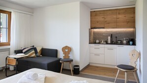 A compact hotel room with a bed, two chairs, a small table, a sofa, and a kitchenette. - Lovely apartment for 2 people with pool, WIFI, TV, balcony, pets allowed and panoramic view (Falera)