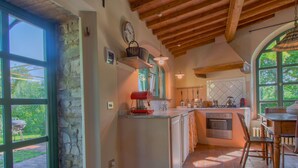 Una cocina con pared de piedra, vigas de madera en el techo y ventanas amplias.