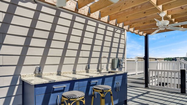 Una cocina al aire libre con encimera azul, dos taburetes y un ventilador de techo.