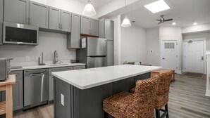 A modern kitchen with grey cabinets, stainless steel appliances, and a central island with bar stools.