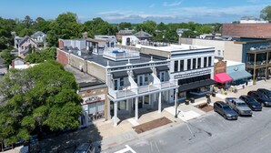 A two-story building with a flat roof, a covered patio area, and a storefront with a sign reading "Cape Charles Distillery".